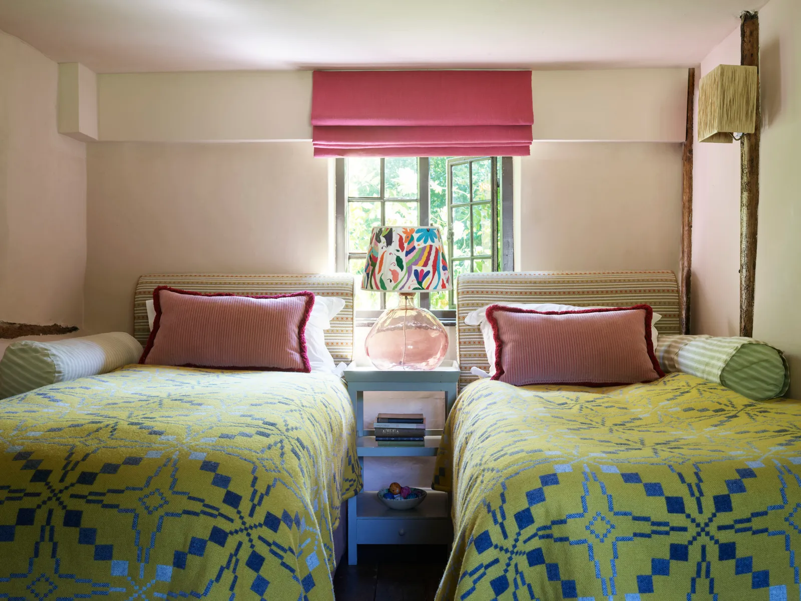 Trong phòng khách ở tầng dưới, 2 giường đơn được phủ chăn kiểu xứ Wales của The Cloth Shop . Đầu giường bằng vải Criss Cross của Christopher Farr Cloth ; Đèn treo tường bằng mây từ Pooky .