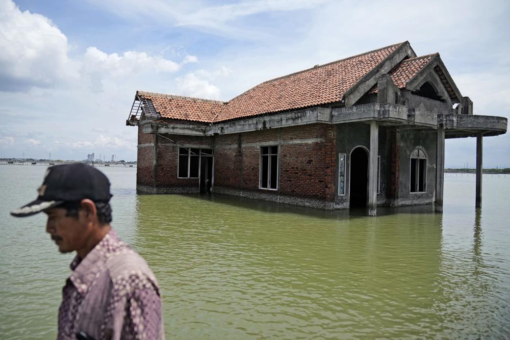 Một người đàn ông đi ngang qua một ngôi nhà bị bỏ hoang sau khi nó bị ngập trong nước do mực nước biển dâng cao ở Sidogemah, Trung Java, Indonesia, ngày 8 tháng 11 năm 2021. Các hiểm họa khí hậu như lũ lụt, sóng nhiệt và hạn hán đã trở nên tồi tệ hơn một nửa trong số hàng trăm bệnh truyền nhiễm đã biết ở người, chẳng hạn như sốt rét, hantavirus, bệnh tả và thậm chí cả bệnh than, theo một nghiên cứu mới được công bố hôm thứ Hai, ngày 8 tháng 8 năm 2022. 
