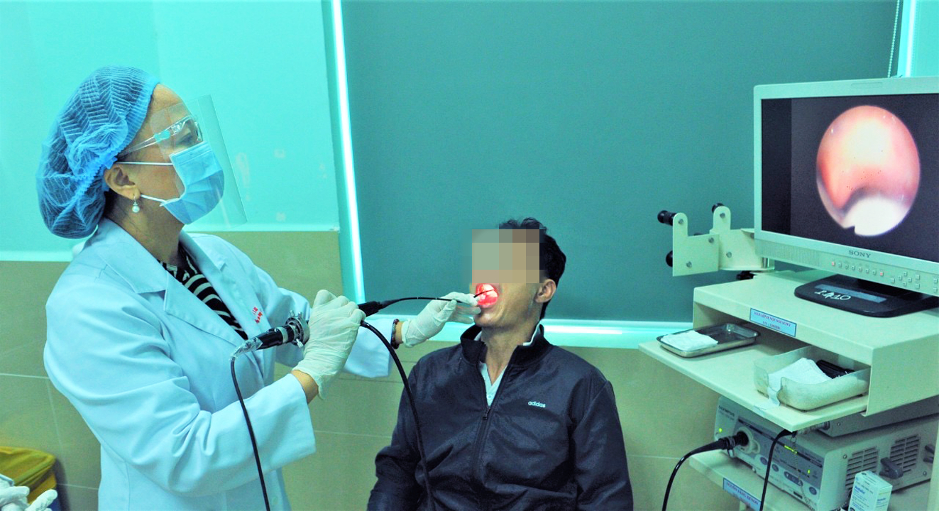 Phó giáo sư - tiến sĩ Trần Phan Chung Thủy kiểm tra tai mũi họng  cho một bệnh nhân