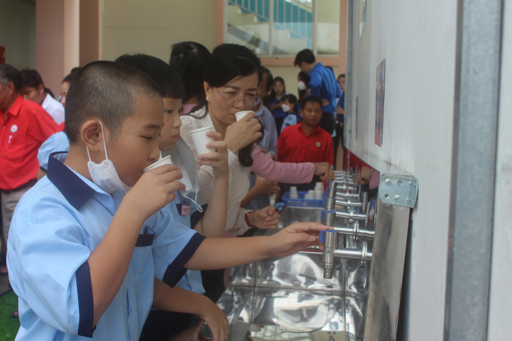 Các học sinh trường tiểu học Qui Đức, H. Bình Chánh dùng nước trong hệ thống lọc.