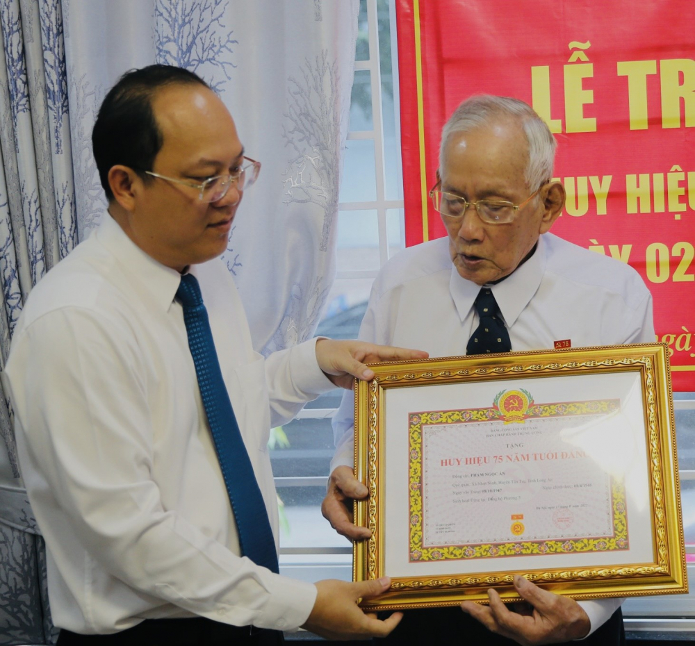 Phó bí thư Thành ủy TPHCM Nguyễn Hồ Hải trao Huy hiệu 75 năm tuổi Đảng cho ông Phạm Ngọc Ẩn - Ảnh: Tường Lam.