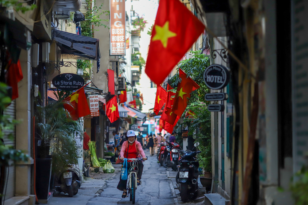 Người dân thảnh thơi đi chợ sớm tại chợ dân sinh trên phố Yên Thái, bên trên là màu cờ Tổ quốc phủ ngợp khắp con phố nhỏ.