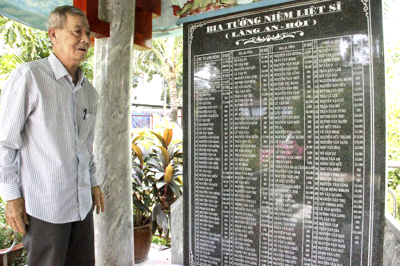 Ông Phạm Văn Hoa bên bia tưởng niệm liệt sĩ làng An Hội được đặt trong đình An Hội nơi ông làm phó ban quản trị
