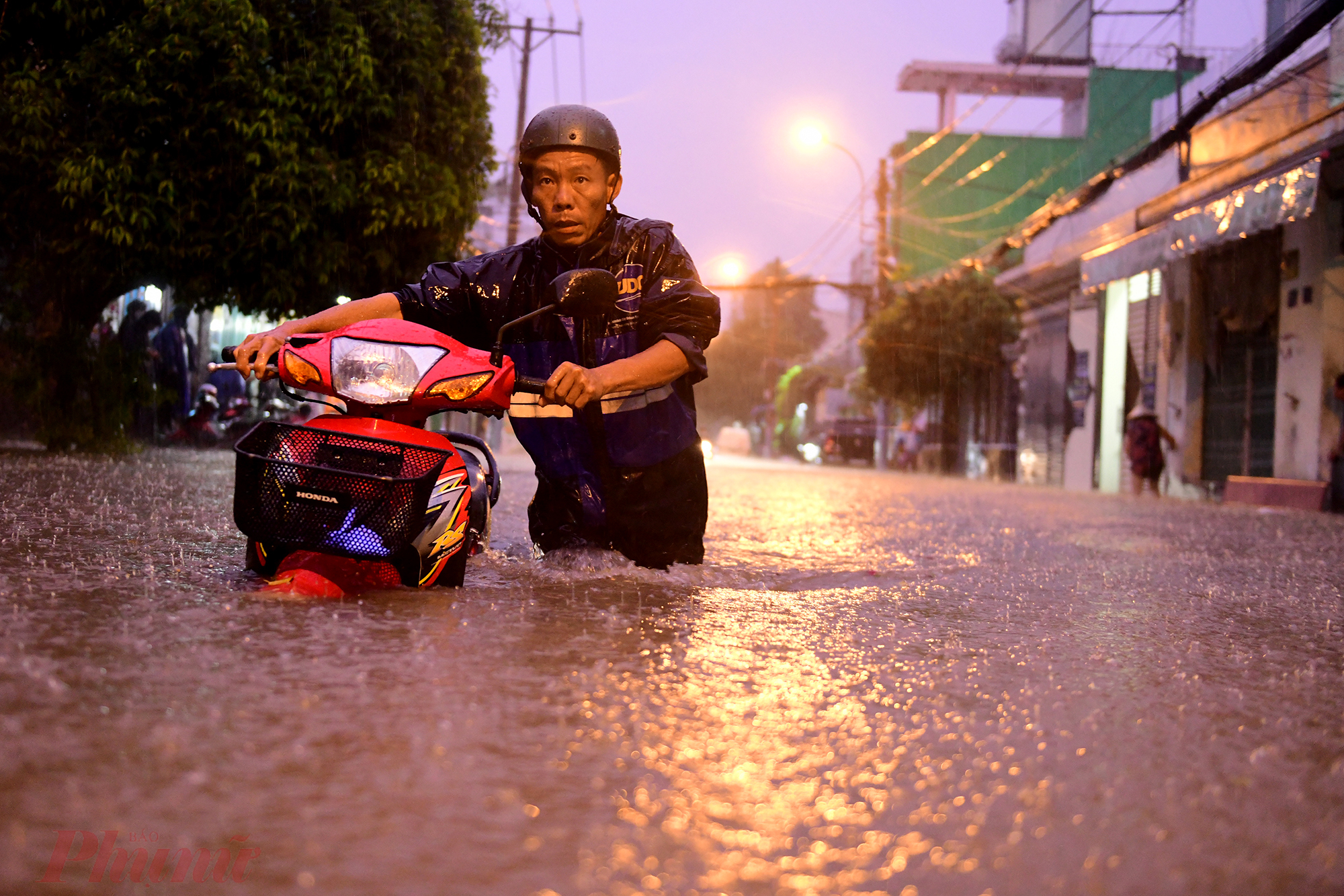 Nước ngập quá nửa xe máy, những đợt sóng liên tục khiến người đàn ông vất vả đẩy xe.