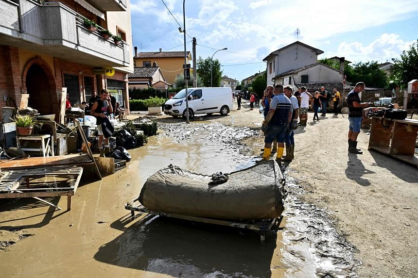  Người dân dọn dẹp một con phố ngập lụt sau trận mưa bom qua đêm ở Pianello di Ostra, Italy. ẢN