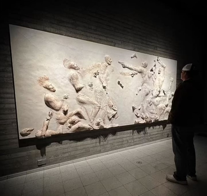 Người xem ngắm một tác phẩm điêu khắc treo tường bằng chất liệu thạch cao, sáng tác của Brad Pitt