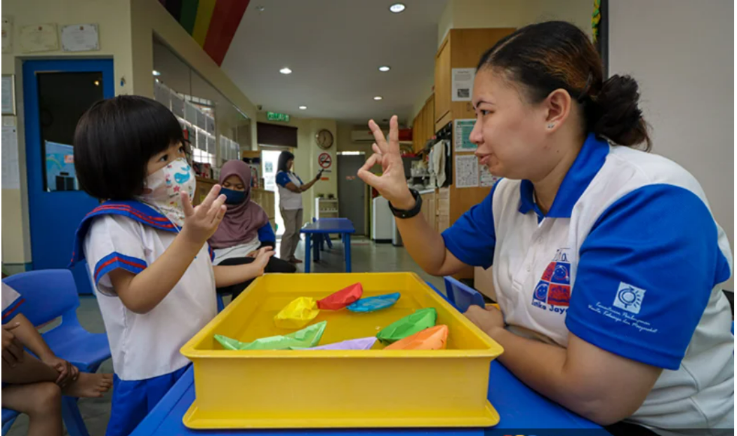 Giáo viên đang dạy trẻ em cách sử dụng ngôn ngữ ký hiệu 