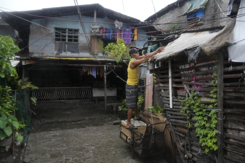 Một cư dân bảo vệ mái nhà của mình tại khu ổ chuột Tondo, Manila