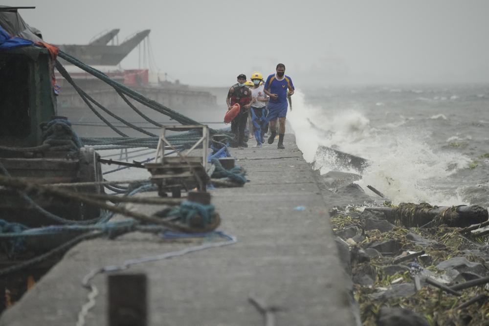 Nhân viên cứu hộ chạy khi họ kiểm tra cư dân sống ở quận khu ổ chuột bên bờ biển của Tondo trong khi Typhoon Noru đến gần Manila, Philippines
