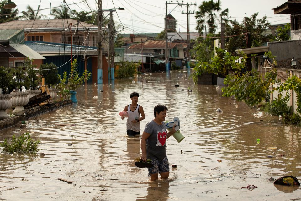Người dân lội qua vùng nước ngập sâu ngang thắt lưng sau siêu bão Noru, ở San Miguel, tỉnh Bulacan, Philippines