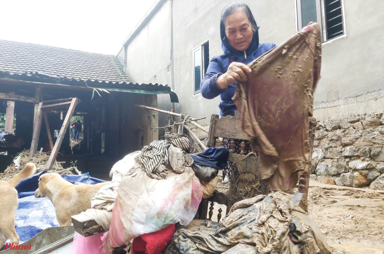 Đôi mắt đỏ hoe, bà Vang Thị Bình (65 tuổi) bảo, may mắn chạy thoát khỏi trận lũ, nhưng nay tài sản trong nhà không còn gì. Sau chừng 30 phút nỗ lực, bà Bình lấy được chiếc tủ đựng quần áo ra khỏi bùn đất. Tuy nhiên, chiếc tủ cũ kỹ chẳng che được, mấy bộ quần áo cũng đã nhuộm bùn non.