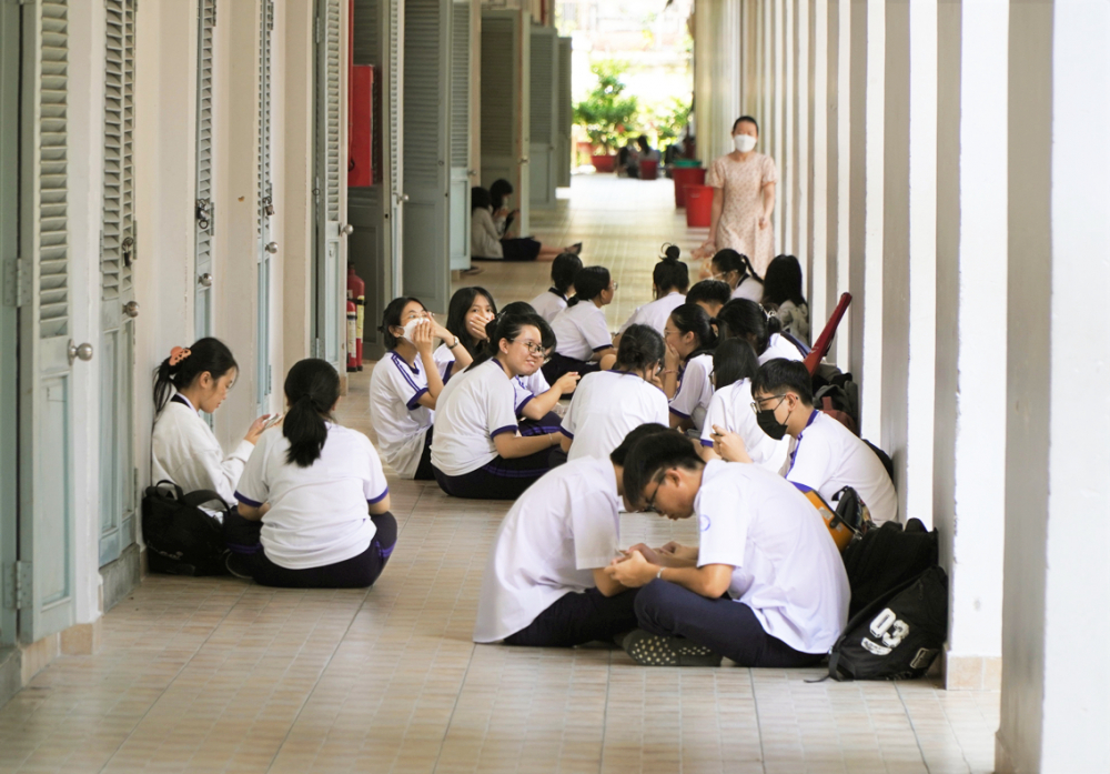 Học sinh Trường THPT Marie Curie (Q.3, TP.HCM) (không đăng ký nghỉ trưa) ngồi ở hành lang chờ giờ học chiều - ẢNH: P.T