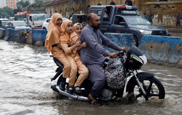 Các em gái ở Pakistan đi học trên đường phố ngập nước vì lũ lụt