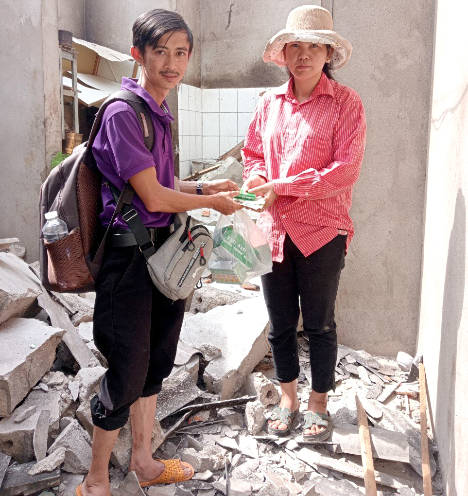 Anh Minh trao tiền, một ít hàng hoá cho cho những gia đình thiệt hại nặng ở xã Tà Cạ