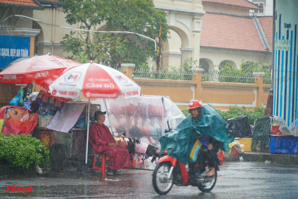 Trời mưa lớn khiến người đi đường không mấy chú ý đến các điểm bán hoa trên đường Nguyễn Văn Cừ 