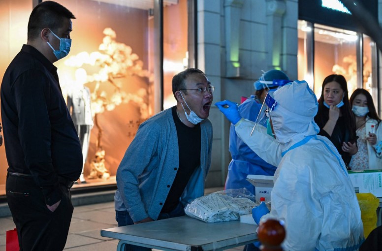 Một nhân viên y tế lấy mẫu tăm bông từ một người đàn ông để xét nghiệm COVID-19 ở quận Hoàng Phố, Thượng Hải hôm thứ Hai. | AFP-JIJI