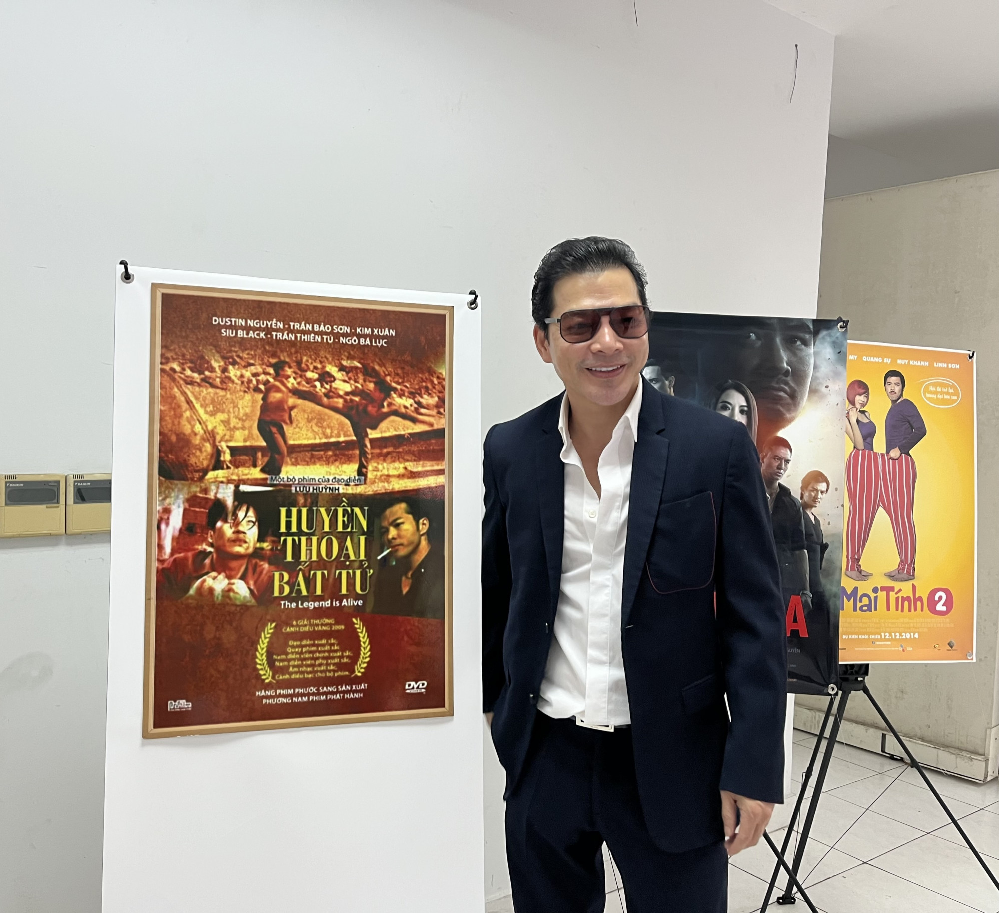 Nam diễn viên Trần Bảo Sơn chụp hình bên poster phim đầu tay anh đóng Huyền thoại bất tử