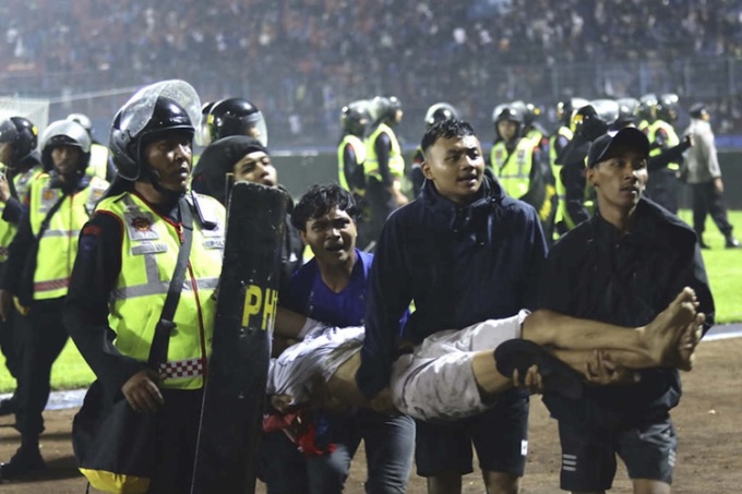 Cảnh sát hỗ trợ đám đông di chuyển người bị thương sau vụ giẫm đạp trên sân vận động tại Indonesia.