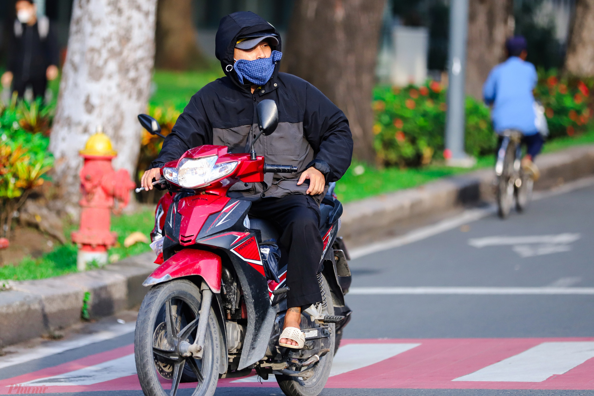 Người đàn ông mang áo khoác dày, trùm kín khi đi trên đường Phạm Ngọc Thạch, quận 1.