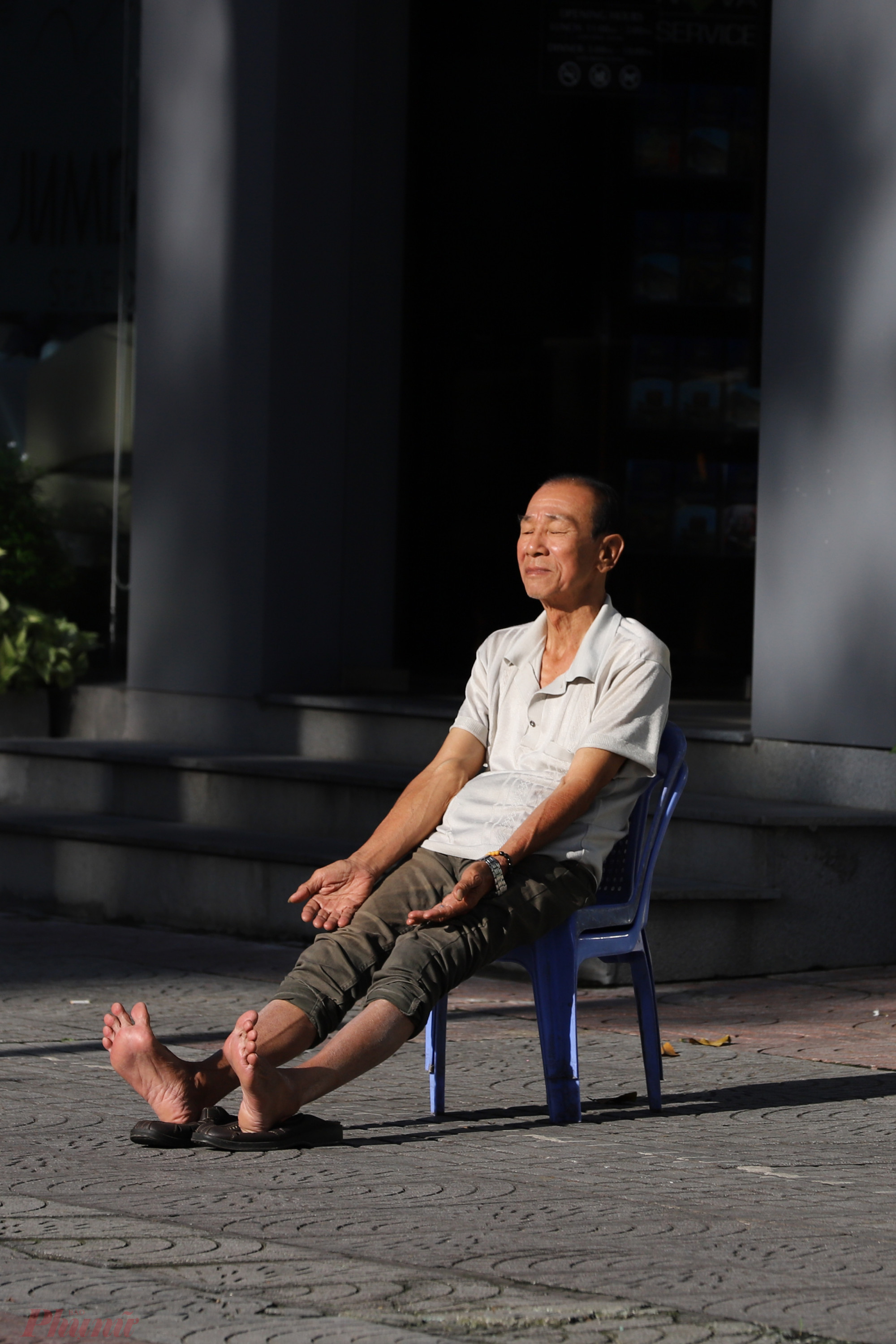 Khoảng hơn 7g sáng, trời bắt đầu hửng nắng, người đàn ông tranh thủ phơi nắng trước nhà trên đường Trần Hưng Đạo, quận 1.