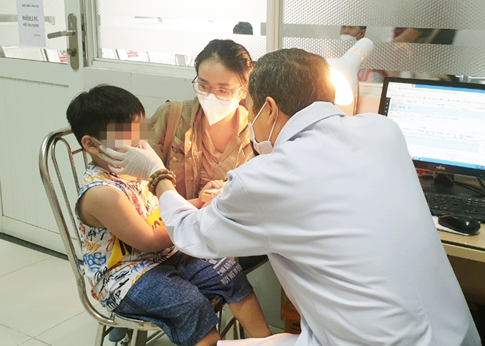Bác sĩ Nguyễn Thành Danh đang khám cho bé trai bị viêm kết mạc - ẢNH: P.A.