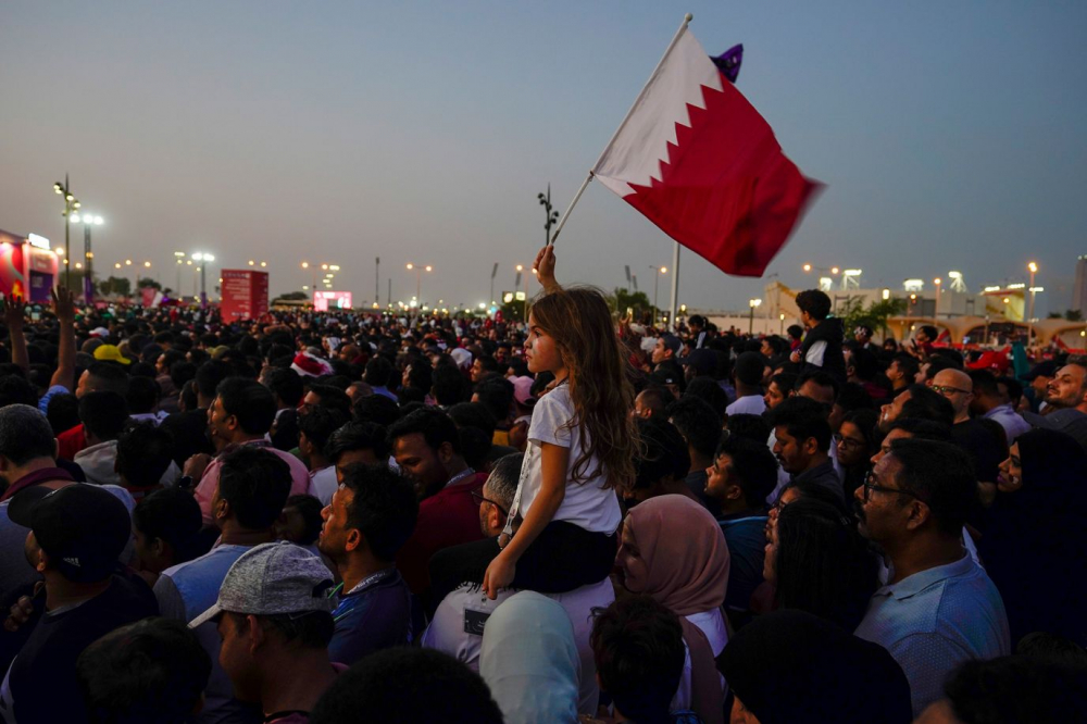 Một bé gái vẫy cờ Qatar trong khi theo dõi lễ khai mạc tại một khu vực dành cho người hâm mộ ở Doha, Qatar