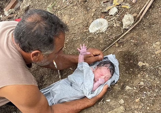 Một người đàn ông bế một bé gái sơ sinh được tìm thấy trong ba lô vào thứ Năm ngày 17 tháng 11