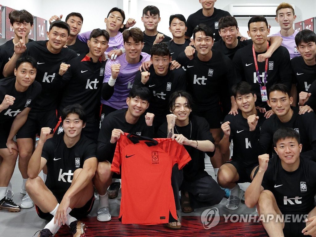 Jungkook cùng tuyển thủ Son Heung-mini cầm áo đỏ bên phải) chụp ảnh lưu niệm cùng đội tuyển Hàn Quốc