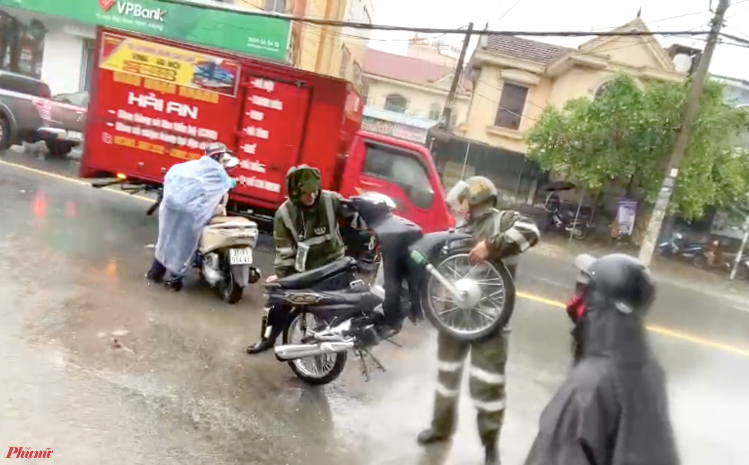 Xe máy chết máy la liệt trên đường, nhiều người nỗ lực “cứu xe” bằng cách dốc ngược để nước ra khỏi ống xả - Ảnh: Khánh Trung