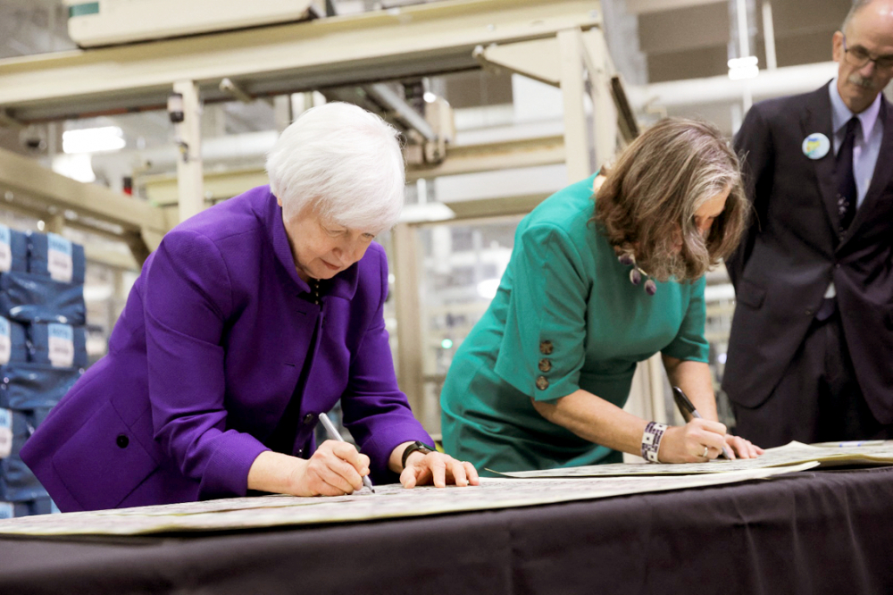 Khoảnh khắc Bộ trưởng Tài chính Janet Yellen (bìa trái) và Giám đốc Ngân khố Lynn Malerba (bìa phải) cùng ký vào  mẫu giấy bạc mới của Mỹ tại cơ sở in tiền Fort Worth (bang Texas) vào ngày 8/12/2022 - ẢNH: REUTERS