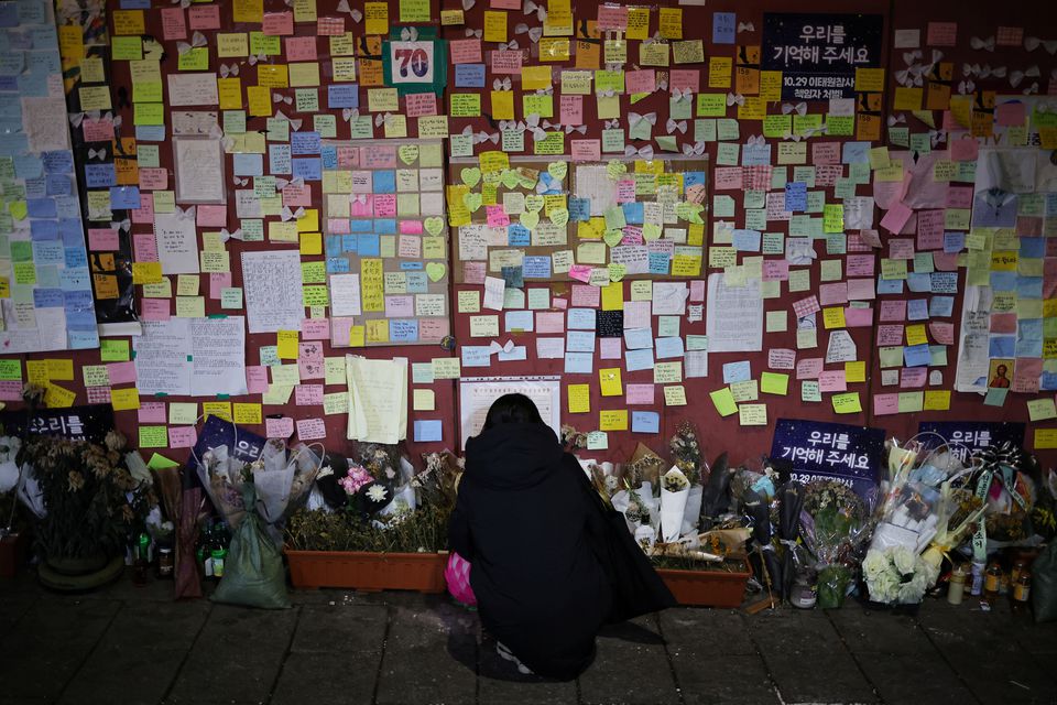 Một người phụ nữ đọc những tin nhắn chia buồn gắn trên bức tường của con hẻm nhỏ ở Itaewon, nơi diễn ra lễ hội Halloween chết chóc