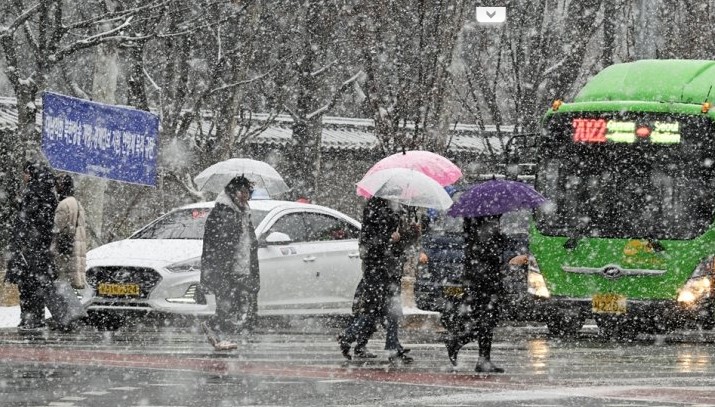 Mọi người băng qua đường khi tuyết rơi ở Seoul vào ngày 15/12. Korea Times đưa tin