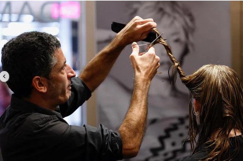 Một thợ làm tóc đang cắt tóc cho khách hàng, tóc sẽ được thu gom để chuyển thành gạch hấp thụ các chất hóa học trong nước, tại một tiệm làm tóc ở Brussels, Bỉ. ẢNH: REUTERS