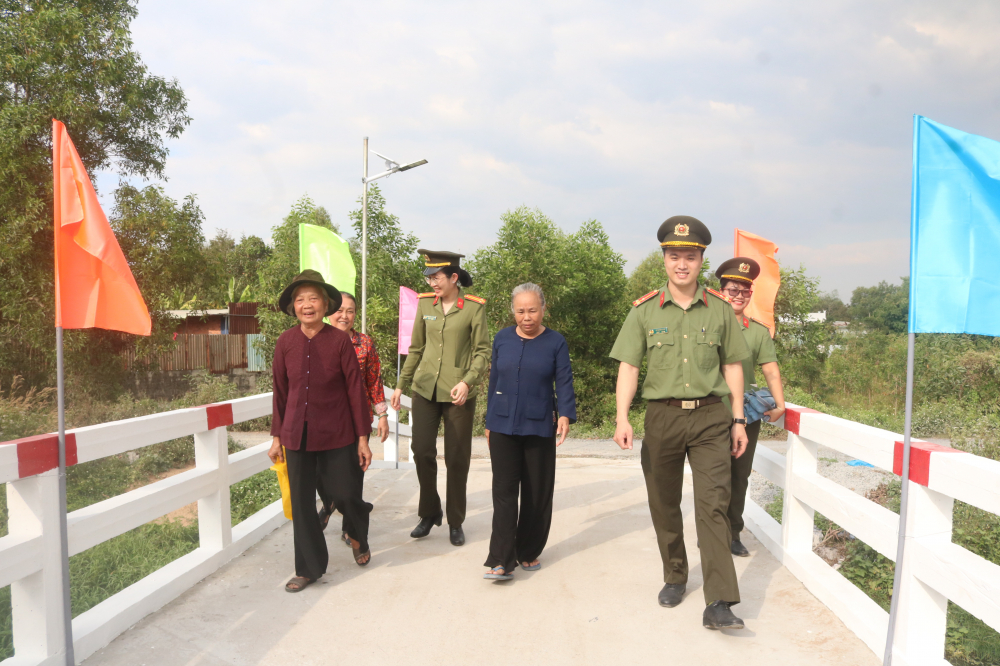 Bà con địa phương cùng cán bộ chiến sĩ Phòng Tổ chức cán bộ Công an TP.HCM cùng bước đi trên cây cầu mới trong niềm phấn khởi. 