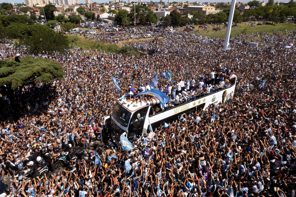 Đội tuyển bóng đá Argentina đi trên một chiếc xe buýt mui trần trong cuộc diễu hành về quê hương của họ ở Buenos Aires, Argentina. Cuộc diễu hành sau đó đã bị tạm dừng vì những lo ngại về an toàn khi hàng triệu người đổ ra đường, đường cao tốc và cầu vượt. (Ảnh: AP)