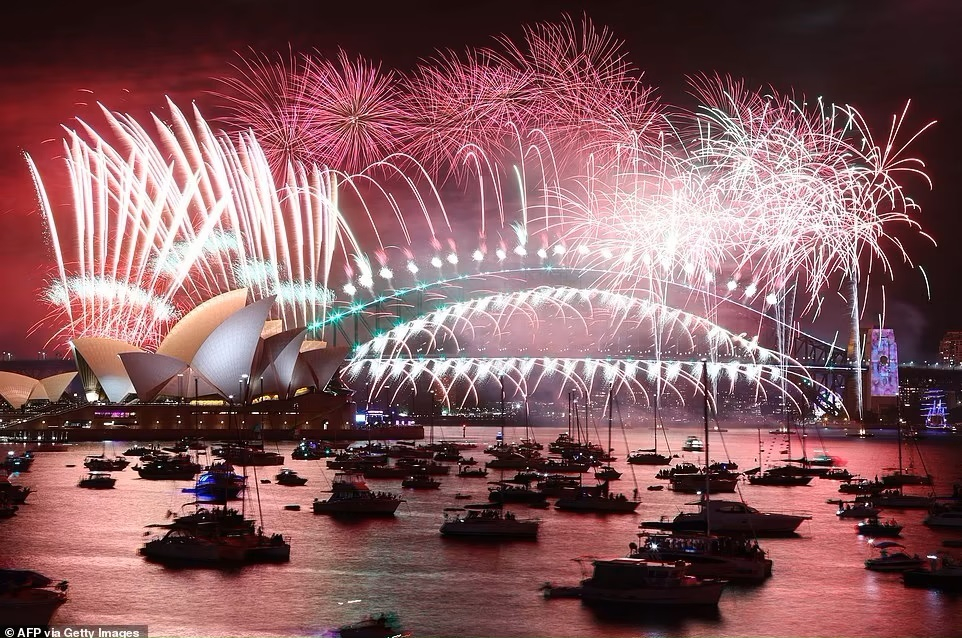 Pháo hoa đêm giao thừa thắp sáng bầu trời Nhà hát Opera Sydney (trái) và Cầu Cảng Sydney