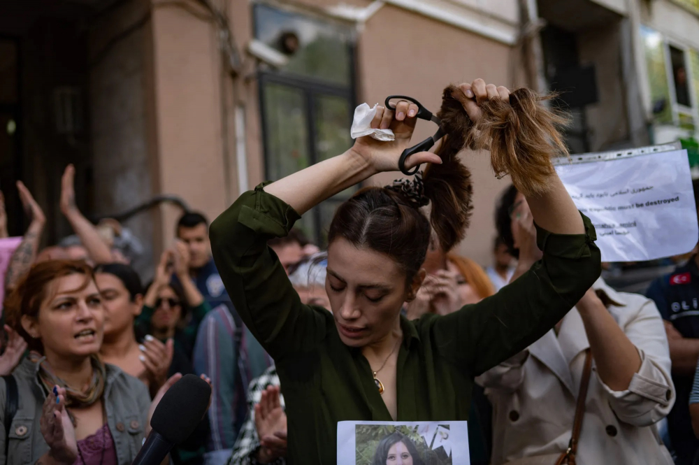 Nasibe Samsaei - một phụ nữ Iran sống ở Thổ Nhĩ Kỳ - cắt đi mái tóc trong cuộc biểu tình bên ngoài lãnh sự quán Iran ở Istanbul, theo sau cái chết của một phụ nữ Iran sau khi cô bị cảnh sát đạo đức của nước này bắt giữ ở Tehran. Mahsa Amini, 22 tuổi, đang cùng gia đình đến thăm thủ đô Tehran của Iran thì bị bắt giữ vào ngày 13/9/2022 bởi đơn vị cảnh sát chịu trách nhiệm thực thi quy định nghiêm ngặt về trang phục đối với phụ nữ, bao gồm cả việc đội khăn trùm đầu ở nơi công cộng . Mahsa Amini được tuyên bố là đã chết vào ngày 16/9 sau ba ngày hôn mê. (Ảnh: AFP)