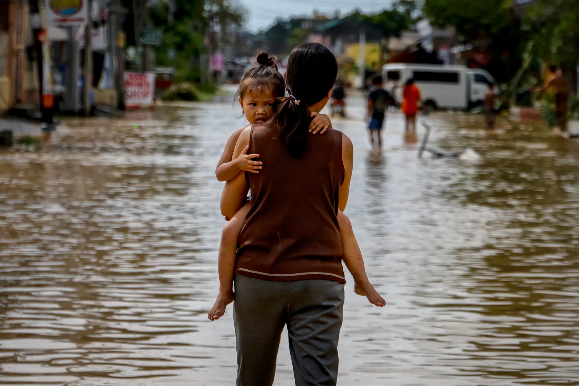 Một người phụ nữ bế con qua dòng nước lũ do siêu bão Noru gây ra ở San Miguel, tỉnh Bulacan, Philippines vào tháng 9. Siêu bão Noru đổ bộ vào Philippines trong đêm, gây lũ lụt trên diện rộng và khiến ít nhất 5 người thiệt mạng. (Ảnh: Getty Images)