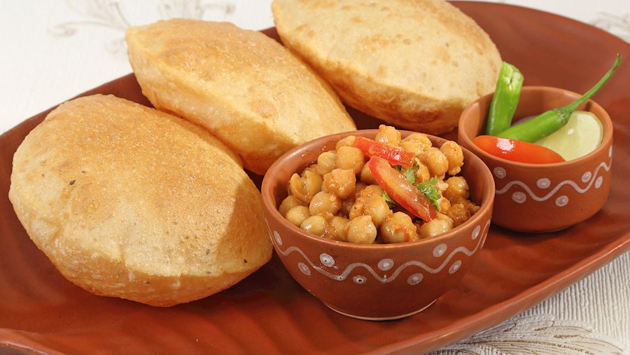 Về cốt lõi, chole bhature là sự kết hợp của hai món ăn: chole - món cà ri đậu xanh cay và bhature - một loại bánh mì chiên làm từ bột maida. Phổ biến khắp Bắc Ấn Độ, món ăn này được phát minh ở Delhi vào những năm 1940.  Nó thường được ăn kèm với hành tây, dưa chua, tương ớt bạc hà và lassi ướp lạnh. Chole bhature có thể được tìm thấy ở hầu hết các xe bán hàng rong ở Bắc Ấn Độ, nhưng nó cũng có thể dễ dàng chuẩn bị tại nhà. Mặc dù có thể ăn vào bất kỳ thời điểm nào trong ngày, nhưng chole bhature đặc biệt phổ biến vào buổi sáng, khi bhature chứa đầy khoai tây hoặc pho mát, khiến nó trở thành một bữa sáng thịnh soạn và bổ dưỡng.