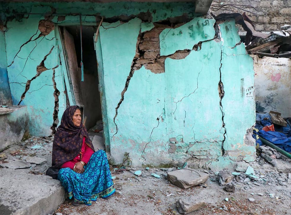 Một cụ bà ngồi cạnh tường nhà đầy vết nứt của cụ ở thị trấn Joshimath - Ảnh: Getty Images