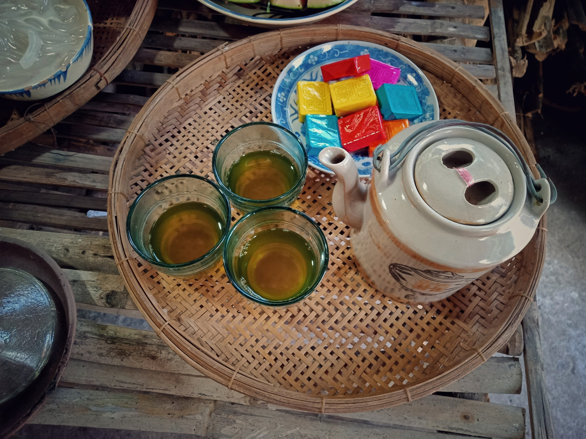 Mâm cúng có bình trà nước cổ xưa, đi kèm với một ít bánh được bọc bởi giấy có màu sắc nổi bật. 