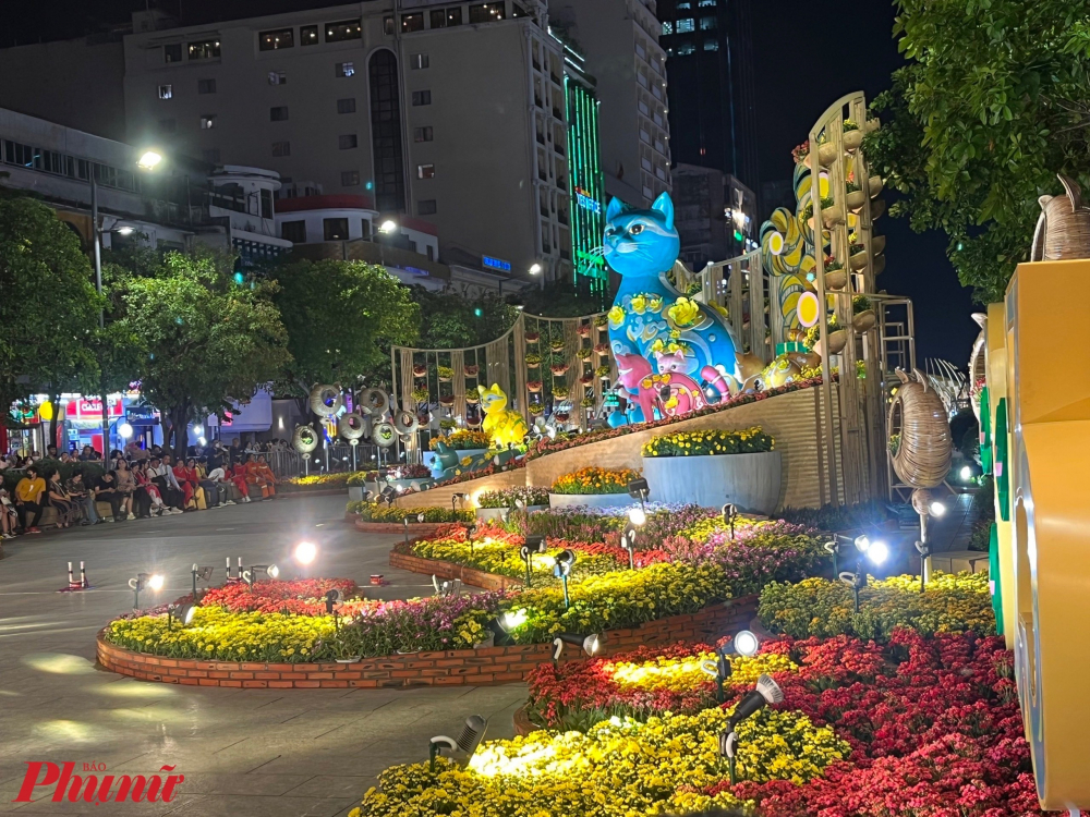 Mèo là linh vật chính năm 2023 có kích thước trung bình trong 12 con giáp nhưng cũng là linh vật duy nhất mà sự uyển chuyển trong cách di chuyển có hẳn một từ riêng để mô tả: “catwalk”. Tại Đường hoa Tết Quý Mão, 70 hình ảnh linh vật mèo được cách điệu thể hiện đa dạng về kích thước (thấp nhất 0,6 m, cao nhất 5,5 m), đa dạng về chất liệu từ mút xốp, sắt, sơn mỹ thuật, phủ mùn cưa, giả đất nung đến ốp hoa tươi… Dưới nhiều sắc thái, biểu cảm khác nhau từ dễ thương, nghiêm túc, tinh nghịch, lười biếng đến tò mò, linh vật Đường hoa năm nay sẽ không gây nhàm chán cho bất kỳ khách tham quan nào đi trọn hơn 600 m Đường hoa. (Trong ảnh: Linh vật mèo tại khu vực cổng chào đầu đường hoa, hướng gần UBND TPHCM).