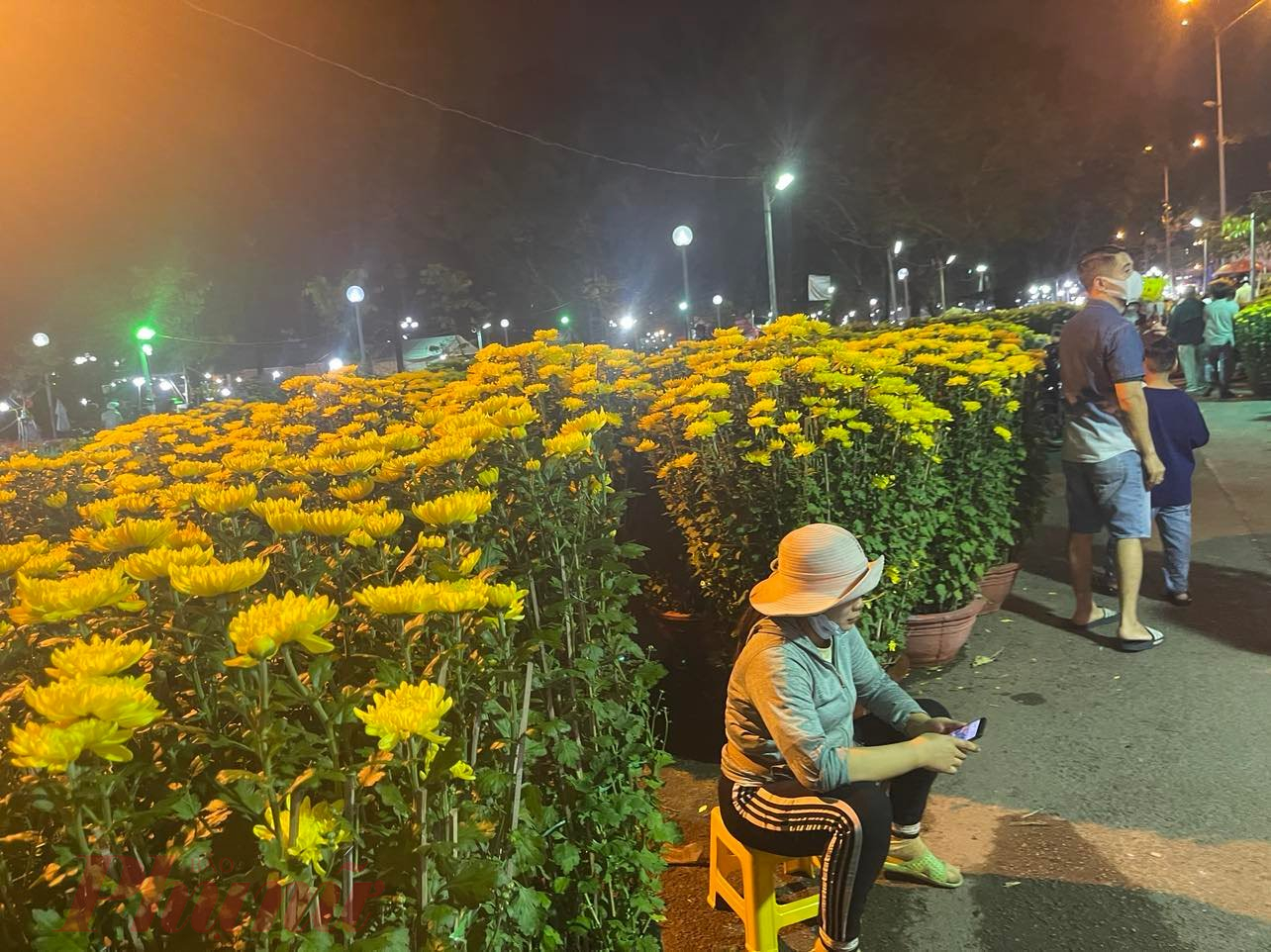 Chị Trang mời khách mua hoa nhưng phần lớn khách lướt qua, chị nói ngồi bấm điện thoại cho đỡ buồn - Ảnh: Nguyễn Cẩm