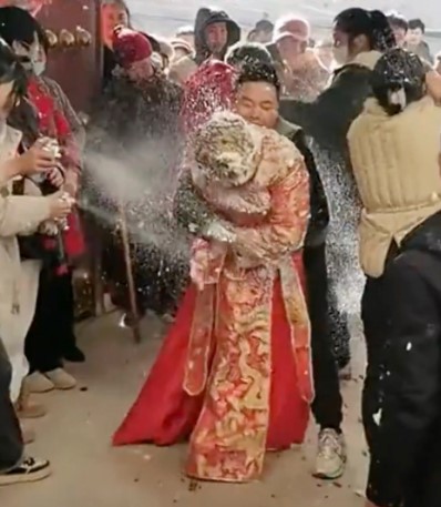 Cô dâu bị một nhóm đàn ông xịt bọt để hoàn thành nghi lễ làm nhục cô. Ảnh: Weibo