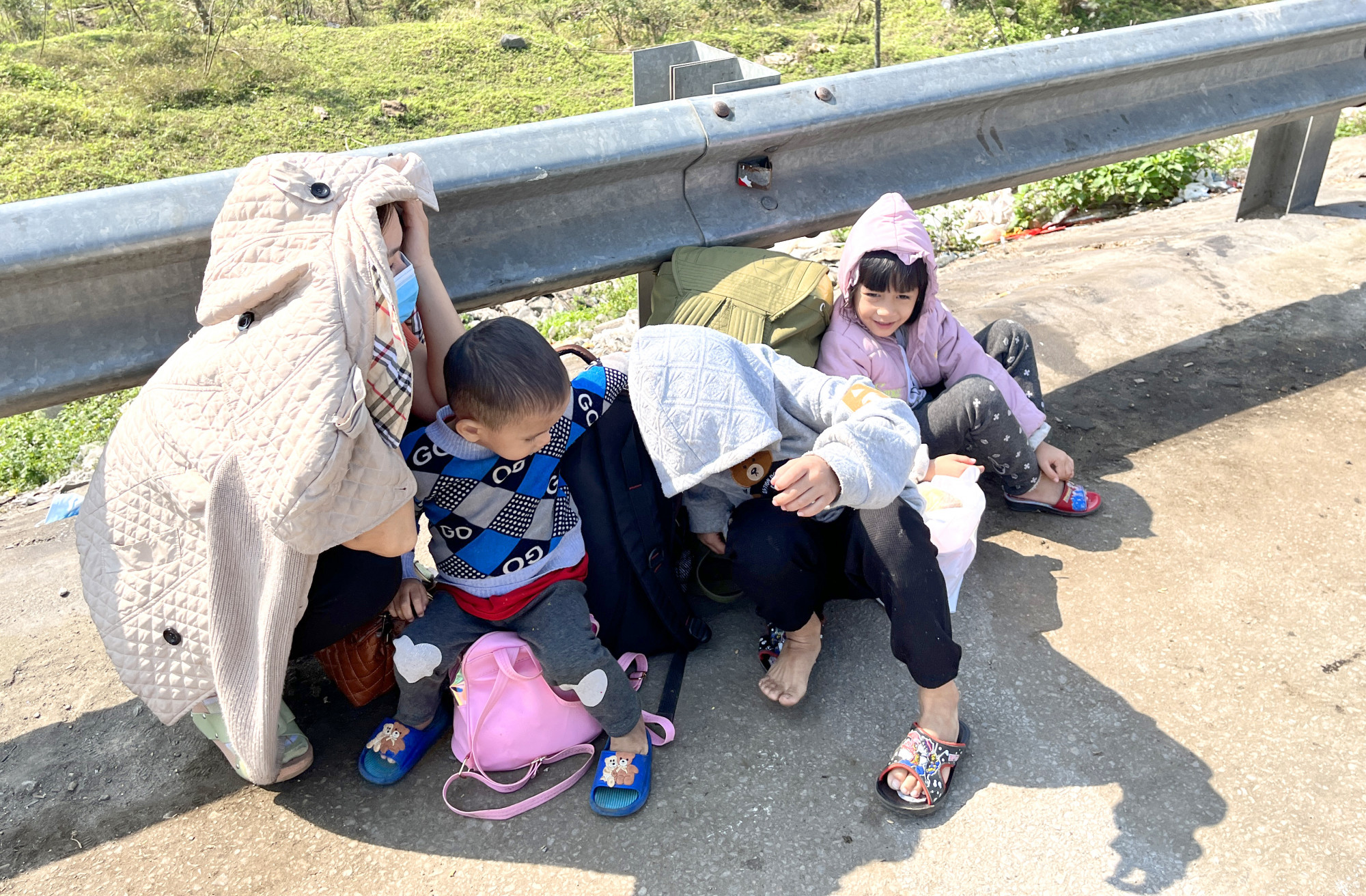 Nhiều trẻ nhỏ ngồi vật vờ bên lề đường cùng bố mẹ đón xe vào miền Nam - Ảnh: Phan Ngọc