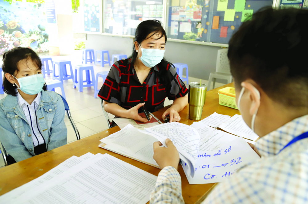 Phụ huynh nộp hồ sơ nhập học vào lớp Sáu cho con tại Trường THCS Lý Thánh Tông (quận 8, TPHCM) - ẢNH: MINH HUY