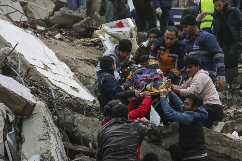 Người dân và đội cứu hộ giải cứu một người nằm trên cáng từ tòa nhà bị sập ở Adana, Thổ Nhĩ Kỳ