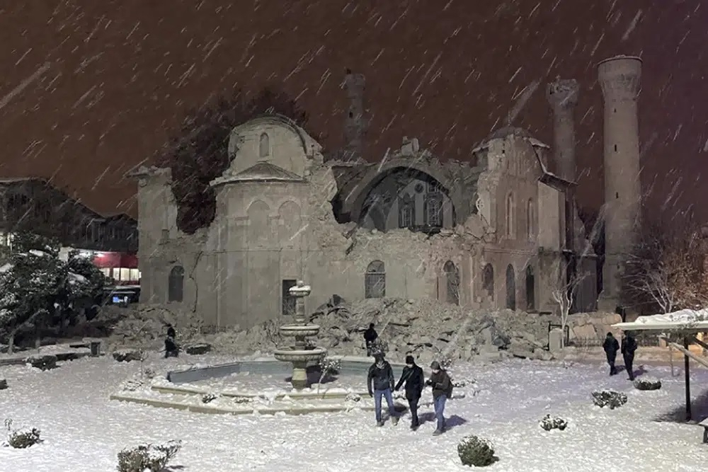 Mọi người đi bộ bên cạnh một nhà thờ Hồi giáo bị phá hủy bởi trận động đất ở Malatya, Thổ Nhĩ Kỳ. Thời tiết lạnh đang cản trở nỗ lực cứu hộ