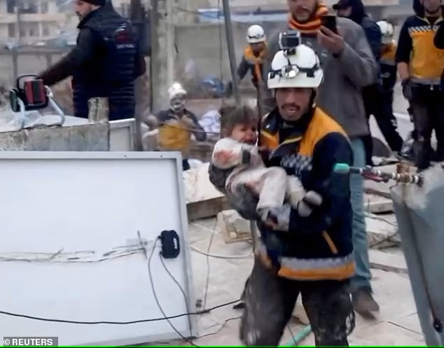 Một nhân viên cứu hộ bế một đứa trẻ bị thương ra khỏi đống đổ nát của một tòa nhà bị sập ở Syria, tại khu vực do quân nổi dậy kiểm soát