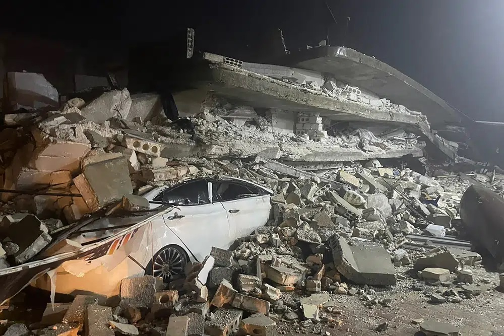 Một chiếc ô tô được nhìn thấy dưới đống đổ nát của một tòa nhà bị sập, ở thị trấn Azmarin, tỉnh Idlib, miền bắc Syria